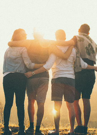group of people standing with their arms wrapped around each other and looking at the sunset